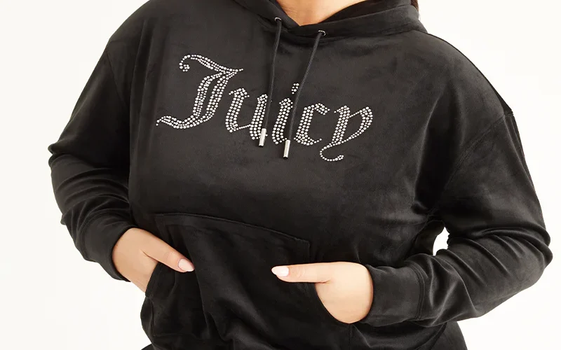 A woman wearing a black hoodie with the word juicy on it. black hoodie